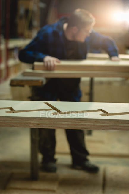 Vista laterale del falegname che misura il legno in officina — Foto stock