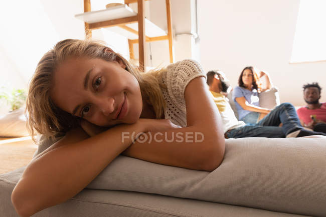 Vorderansicht einer Frau, die es sich zu Hause auf dem Sofa gemütlich macht, während sie in die Kamera schaut — Stockfoto