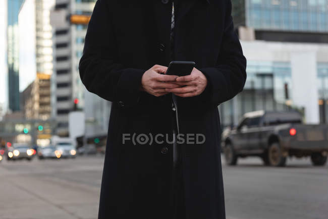Средняя секция молодого азиатского бизнесмена, использующего мобильный телефон на улице — стоковое фото