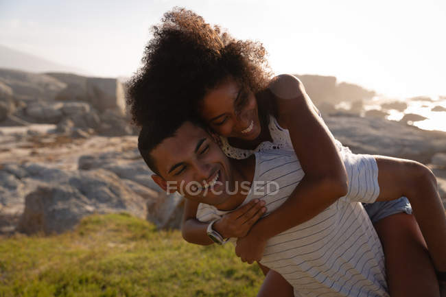 Front view of African-american man giving piggyback ride to woman — Stock Photo