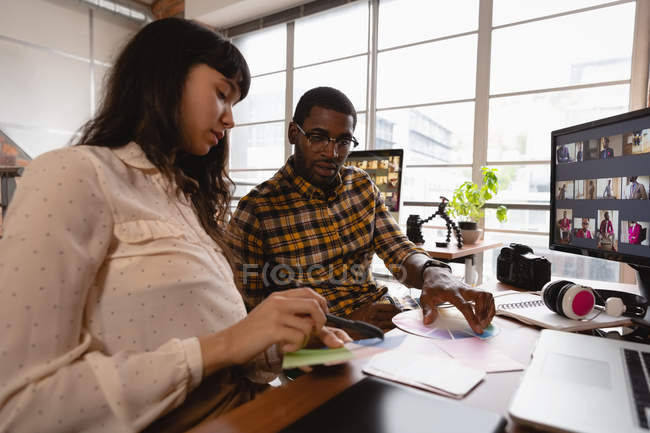 Vista a basso angolo di riflessivo diversi uomini d'affari discutendo sopra campione di colore in ufficio — Foto stock