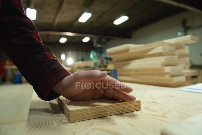 Nahaufnahme eines Tischlers, der in der Werkstatt arbeitet. seine Hand wird auf ein Holzbrett gelegt — Stockfoto