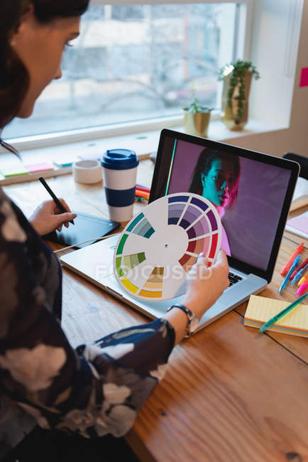 High-Winkel-Ansicht der jungen Geschäftsfrau mit Grafik-Tablet während der Arbeit am Laptop im Büro — Stockfoto