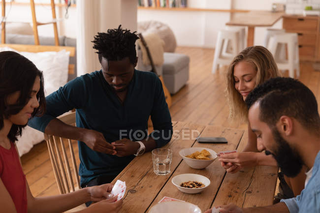 Vue grand angle de couple multi ethnique jouant des voitures à la maison tout en étant assis à la table à manger — Photo de stock