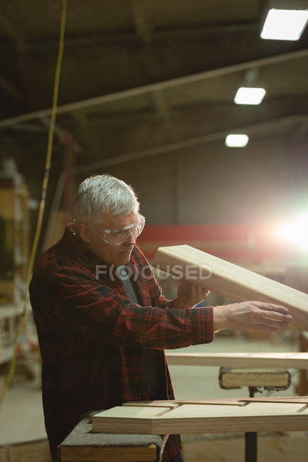 Вид сбоку плотника, измеряющего дерево в мастерской — стоковое фото