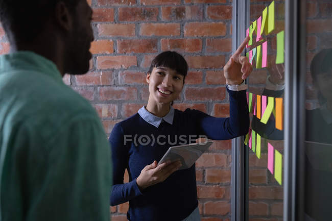 Front view of diverse business people smiling discussing over sticky note in office — Stock Photo