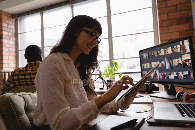 Vista de ángulo bajo de la mujer de negocios caucásica sonriendo y trabajando sobre la tableta digital en la oficina - foto de stock