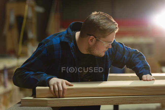 Vista lateral do carpinteiro fazendo medições de madeira na oficina — Fotografia de Stock
