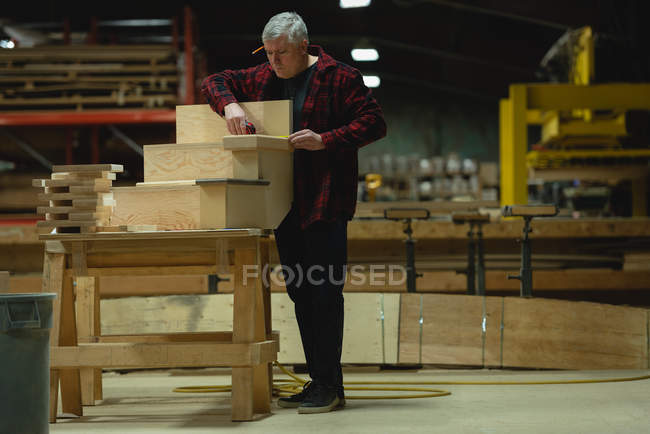 Frontansicht des Tischlers beim Messen von Holzplanken mit Maßband in der Werkstatt — Stockfoto