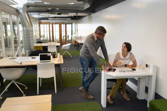 Фронтальный вид многоэтнических бизнесменов, взаимодействующих и обсуждающих синий принт в офисе — стоковое фото