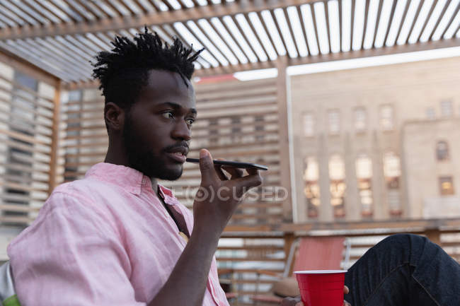 Low-Winkelansicht eines afrikanisch-amerikanischen Mannes, der zu Hause auf dem Balkon mit dem Handy spricht — Stockfoto