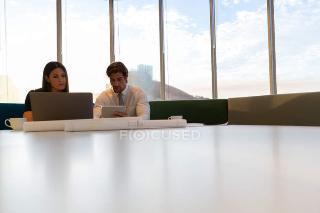 Vista frontal de jóvenes ejecutivos trabajando en la mesa en una oficina moderna - foto de stock