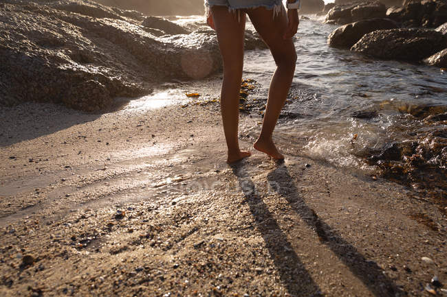 Section basse de la femme debout sur la plage — Photo de stock