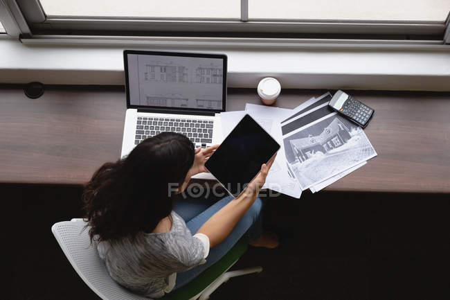 Высокий угол обзора деловой женщины с помощью цифрового планшета в офисе за столом — стоковое фото
