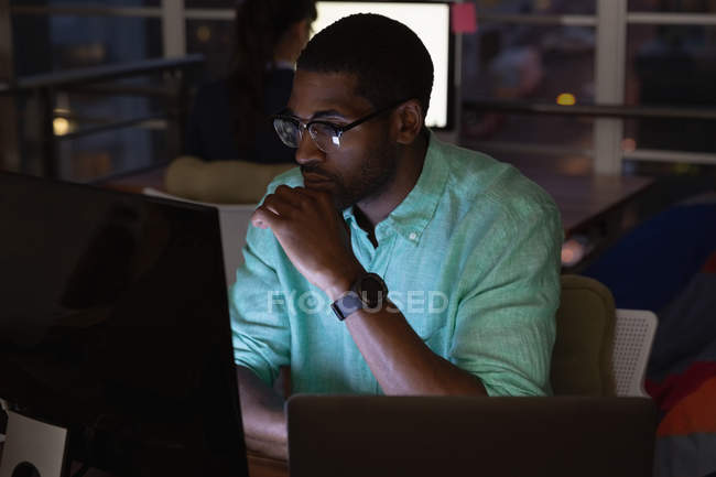 Vue de face d'un homme d'affaires afro-américain travaillant sur ordinateur au bureau — Photo de stock