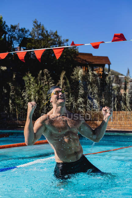 Frontansicht eines aufgeregten männlichen Schwimmers, der seinen Sieg im Schwimmbad feiert — Stockfoto