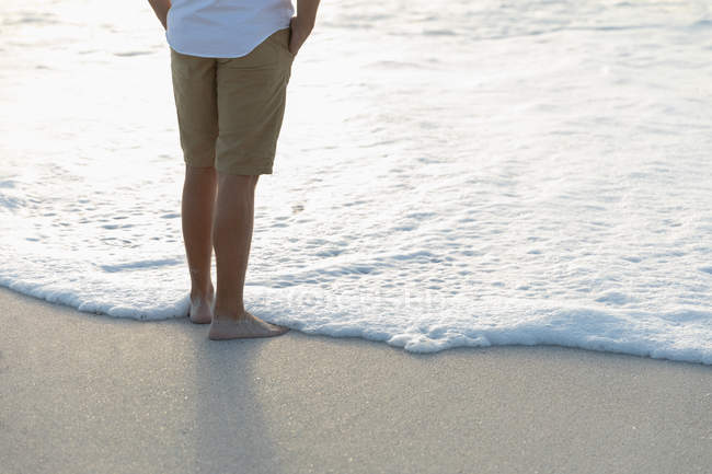 Низька частина розслабленого чоловіка, що стоїть на пляжі в сонячний день. Він насолоджується відпусткою — стокове фото