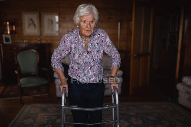 Vue de face d'une femme âgée active marchant avec une marchette dans le salon à la maison — Photo de stock