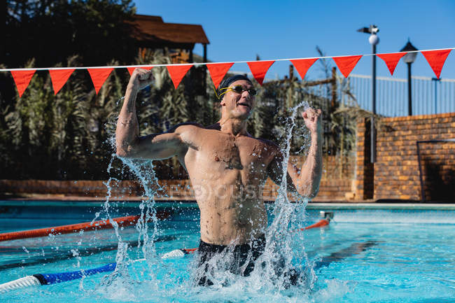 Frontansicht eines aufgeregten männlichen Schwimmers, der seinen Sieg im Schwimmbad feiert — Stockfoto