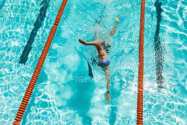 Blick aus der Vogelperspektive auf junge kaukasische Schwimmer, die an sonnigen Tagen Freistil im Schwimmbad schwimmen — Stockfoto