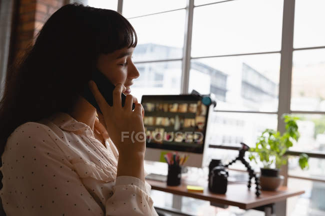 Side view of business woman talking on mobile phone in office — стоковое фото