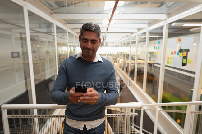 Vista frontale dell'uomo d'affari che utilizza il suo telefono cellulare in ufficio — Foto stock