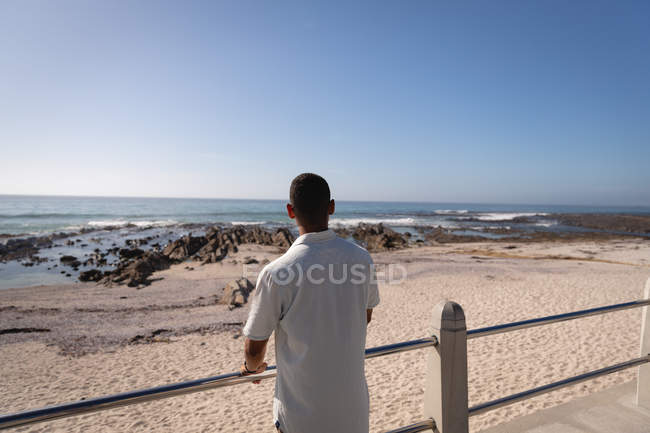 Вид сзади на человека, стоящего на пляже. Глядя на горизонт — стоковое фото
