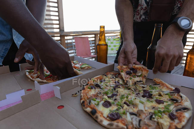 Parte centrale del gruppo di amici che si godono la pizza party in balcone a casa — Foto stock