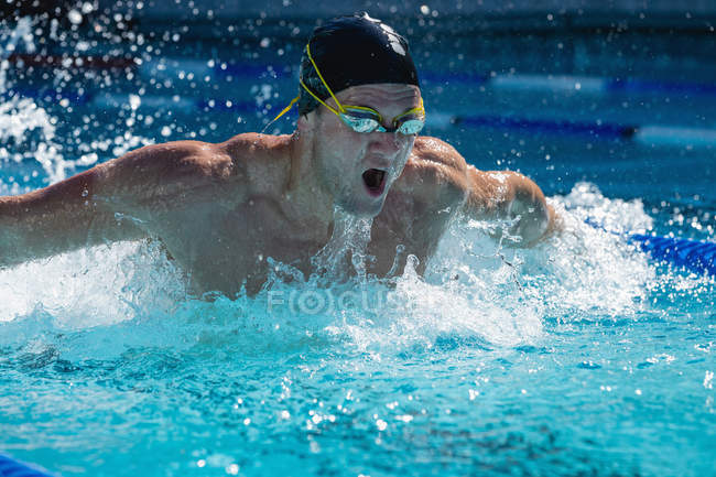 Vista frontal de um nadador masculino nadador estilo livre borboleta na piscina em um dia ensolarado — Fotografia de Stock