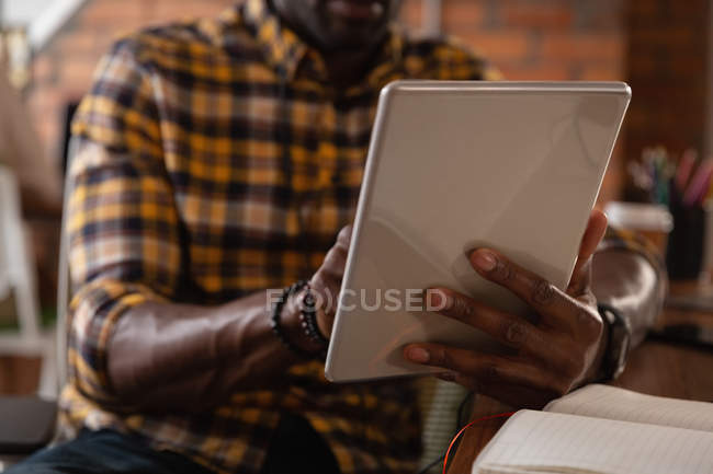 Sección media del hombre de negocios afroamericano usando tableta digital en la oficina - foto de stock