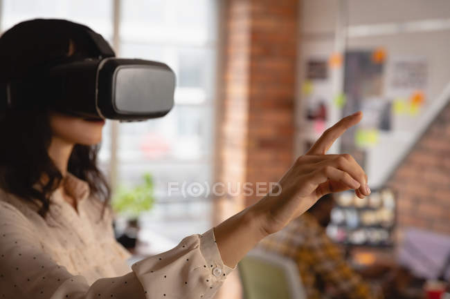 Visão lateral da mulher de negócios usando headset realidade virtual no escritório — Fotografia de Stock