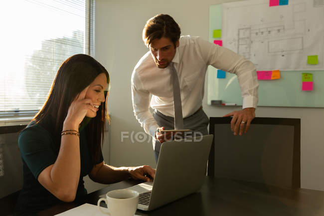 Frontansicht junger Führungskräfte, die in einem modernen Büro am Laptop arbeiten und diskutieren — Stockfoto