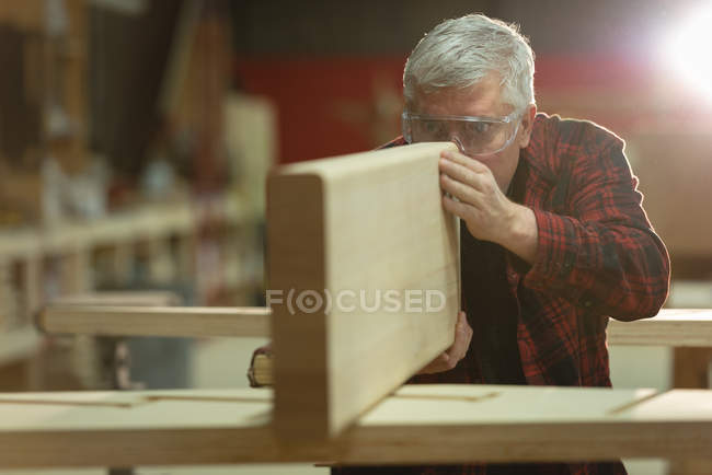 Vue de face du menuisier prenant des mesures de bois à l'atelier — Photo de stock