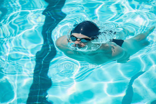 Front view of young Caucasian male swimmer emerging from water in outdoor swimming pool on a sunny day — Stock Photo