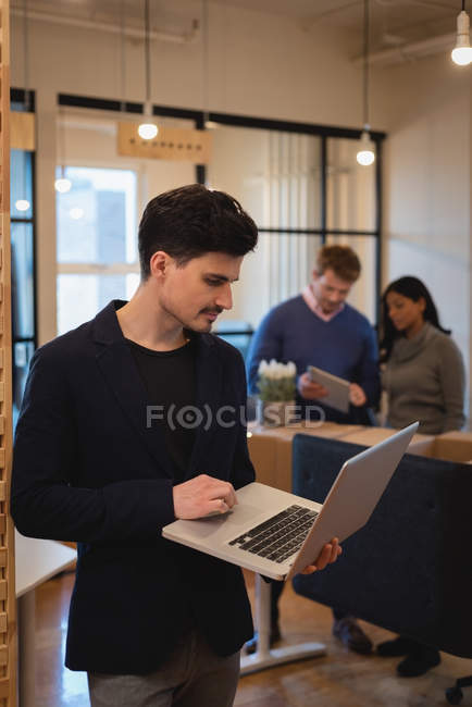 Вид спереди бизнесмена, стоящего и работающего над ноутбуком на офисной конференции — стоковое фото
