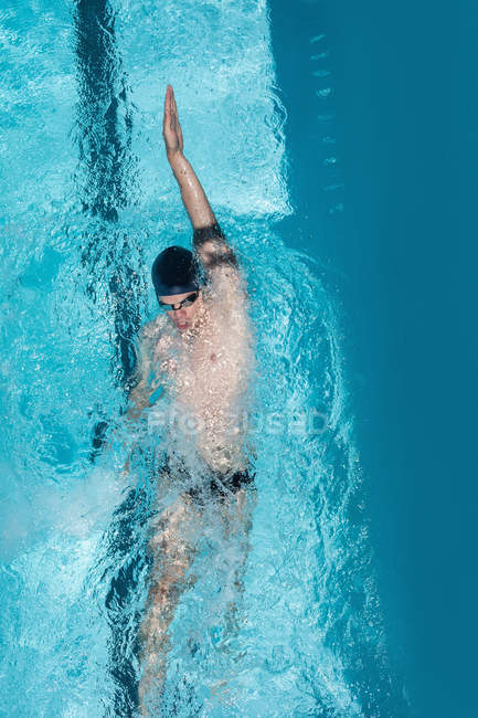 High angle view of young Caucasian male swimmer swimming backstroke in outdoor swimming pool on sunny day — Stock Photo