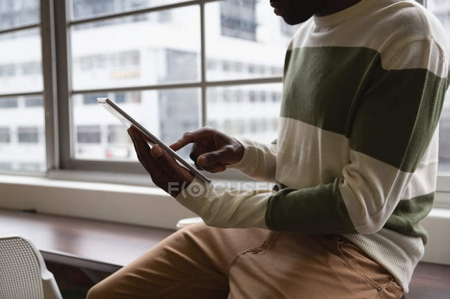 Средняя секция афро-американского бизнесмена, использующего цифровой планшет в офисной столовой — стоковое фото