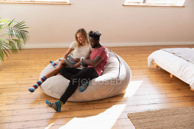 Vista de ángulo alto de la pareja multiétnica utilizando tableta digital en el dormitorio en casa - foto de stock