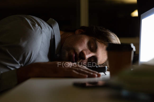 Vue latérale du jeune cadre masculin dormant au bureau dans un bureau moderne — Photo de stock