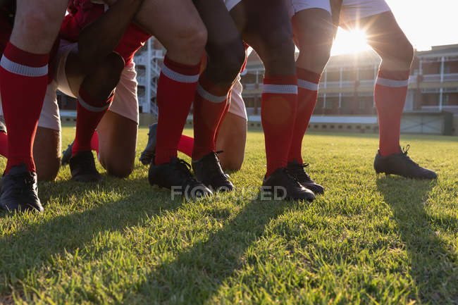 Sección baja de jugadores de rugby masculino preparándose para un scrum en el estadio en un día soleado - foto de stock