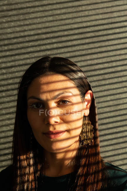 Портрет красивой молодой исполнительницы, стоящей у стены и смотрящей в камеру в современном офисе — стоковое фото