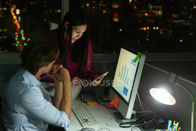 Side view of multi-ethnic young office executives working and discussing over digital tablet at desk in a modern office — Stock Photo