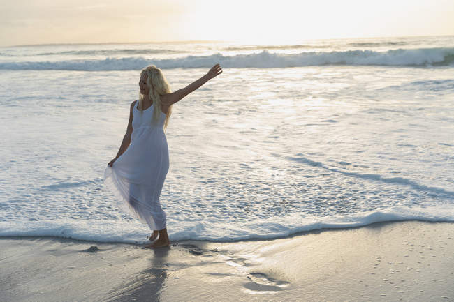 Вид спереду красива жінка позує, стоячи на пляжі в сонячний день. Вона щаслива — стокове фото