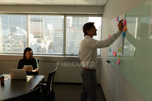 Side view of handsome young attentive office executives working in a modern office. Mixed-race coworker in the background — Stock Photo