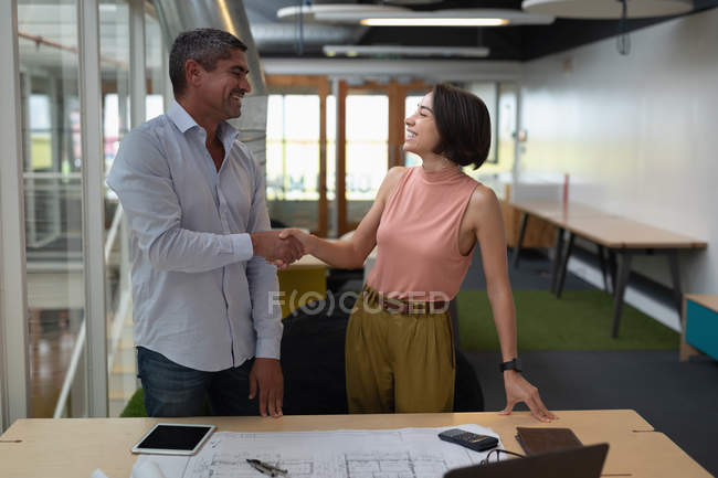 Вид спереду багато етнічних бізнесменів взаємодіють, коли рука трясе один одного в офісі — стокове фото