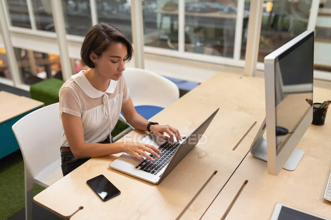 Visão de alto ângulo de uma mulher de negócios asiática trabalhando em seu laptop na mesa no escritório — Fotografia de Stock