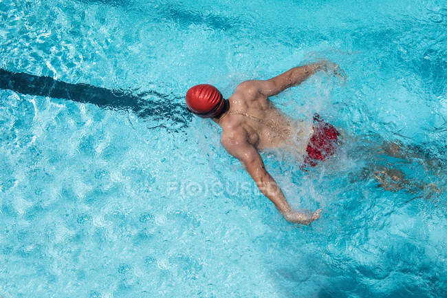 Vista de alto ângulo do jovem nadador branco nadador nadar acidente vascular cerebral borboleta na piscina ao ar livre ao sol — Fotografia de Stock