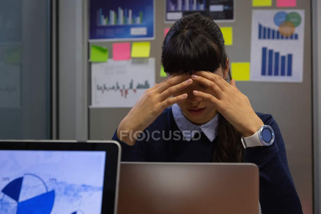 Frontansicht einer Geschäftsfrau, die deprimiert im Büro am Schreibtisch sitzt — Stockfoto