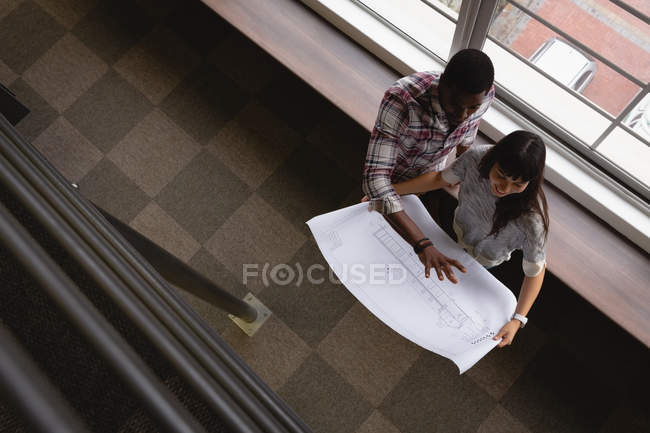 High angle view of diverse business people discussing over blueprint in office at desk. — Stock Photo
