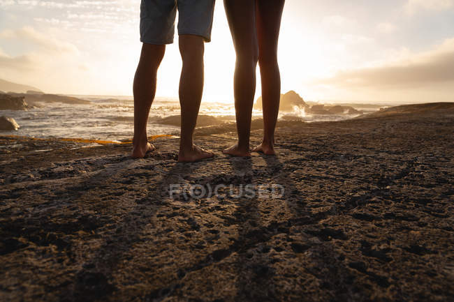 Section basse du couple afro-américain debout et relaxant près du bord de mer — Photo de stock